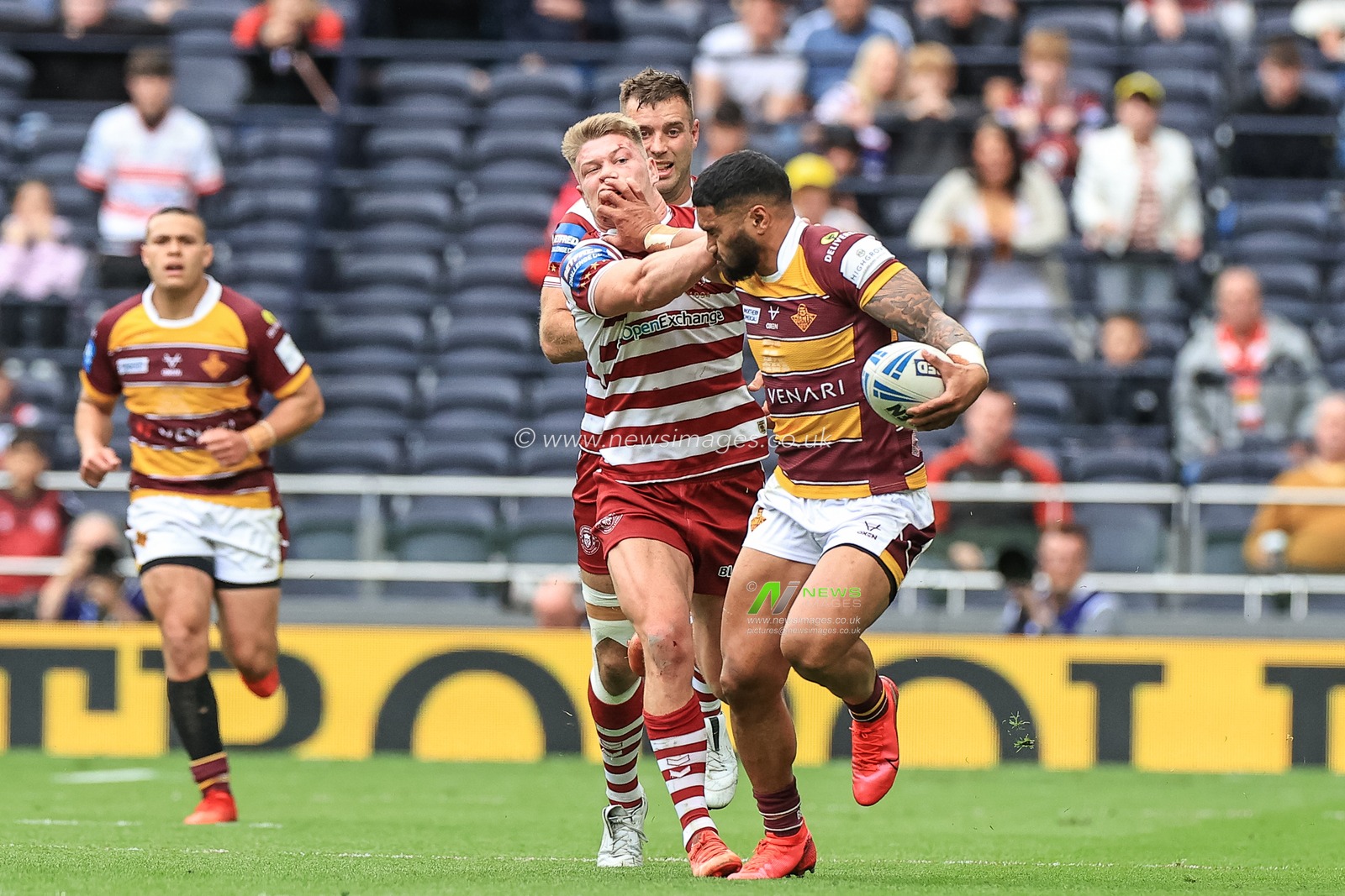 Ricky Leutele #4 of Huddersfield Giants holds off Morgan Smithies #14 of Wigan Warriors