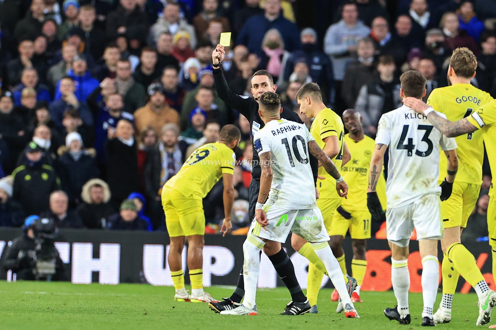 Referee David Coote gives Raphinha #10 of Leeds United a yellow card