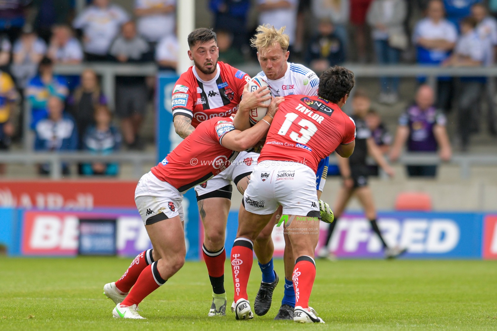 Matt Prior (10) of Leeds Rhinos is tackled by Elijah Taylor (13) of Salford Red Devils and Andy Ackers (9) of Salford Red Devils
