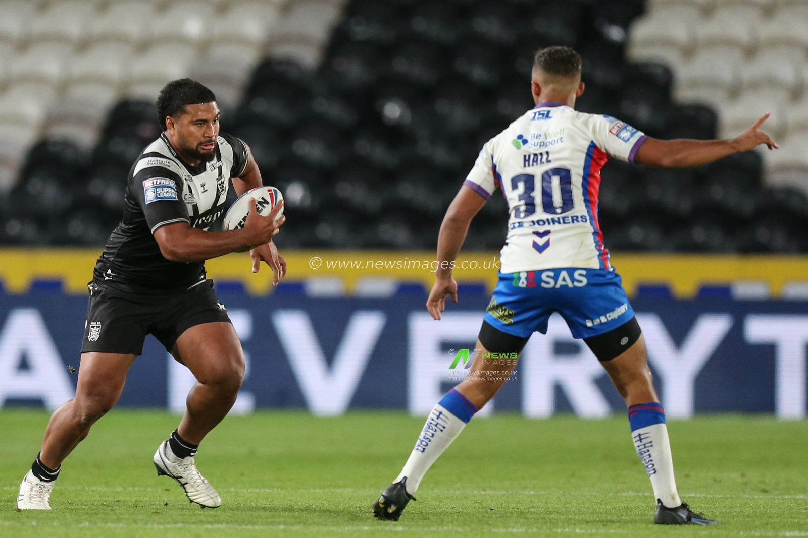 Chris Satae #10 of Hull FC runs at Corey hall #30 of Wakefield Trinity