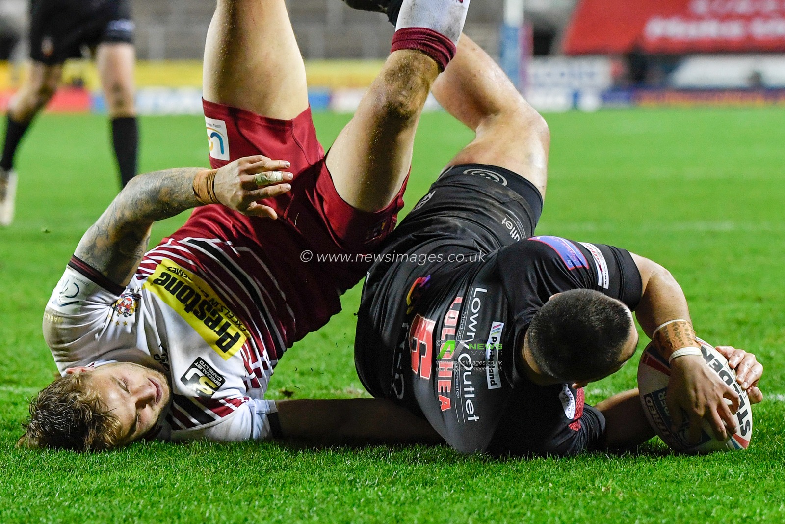 Tui Lolohea (6) of Salford Red Devils goes over for a try under pressure from Sam Powell (9) of Wigan Warriors