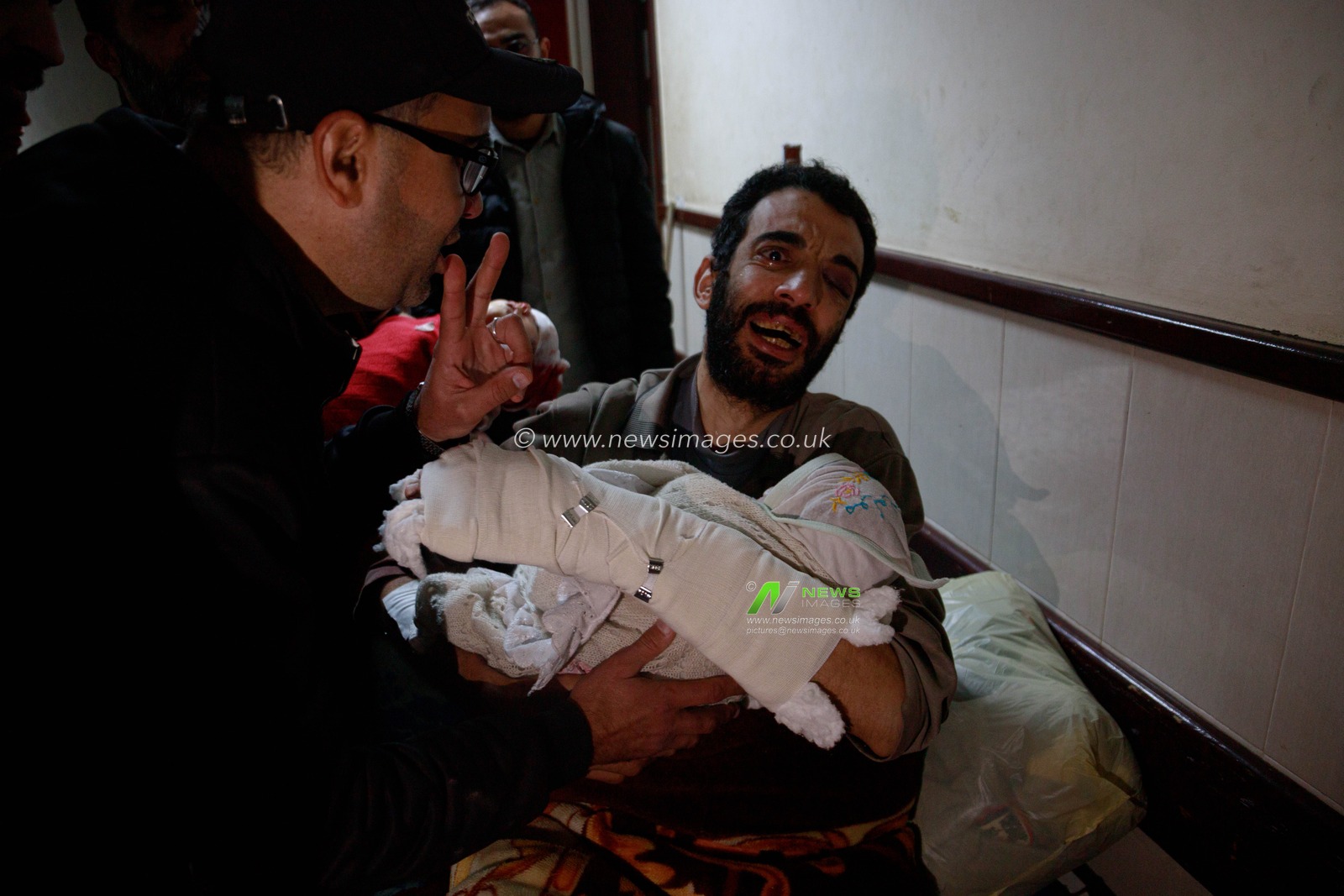 An injured father bids farewell to his son and daughter at Al-Aqsa Martyrs Hospital, who were killed in an Israeli bombing that targeted their home in Deir al-Balah this morning, in addition to their mother who was killed in the same attack.(Photo: Mohammed Skaik/News Images)