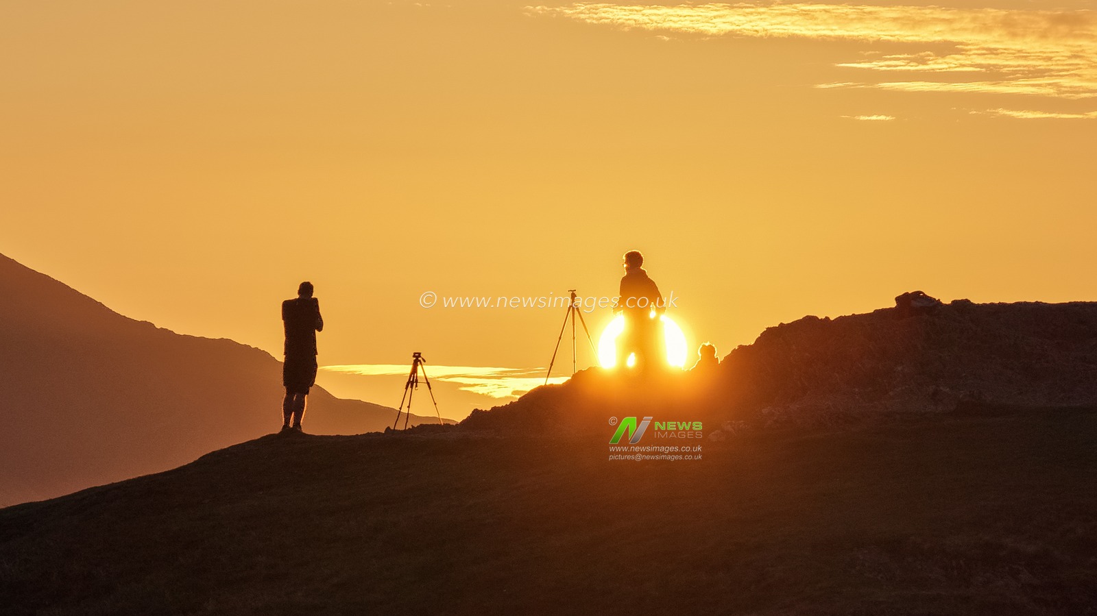 Photographers take pictures as the sun rises from the summit of Catbells overlooking Derwent Water and the town of Keswick In the Lake District, Cumbria, United Kingdom, 19th June 2025

(Photo by Mark Cosgrove/News Images)