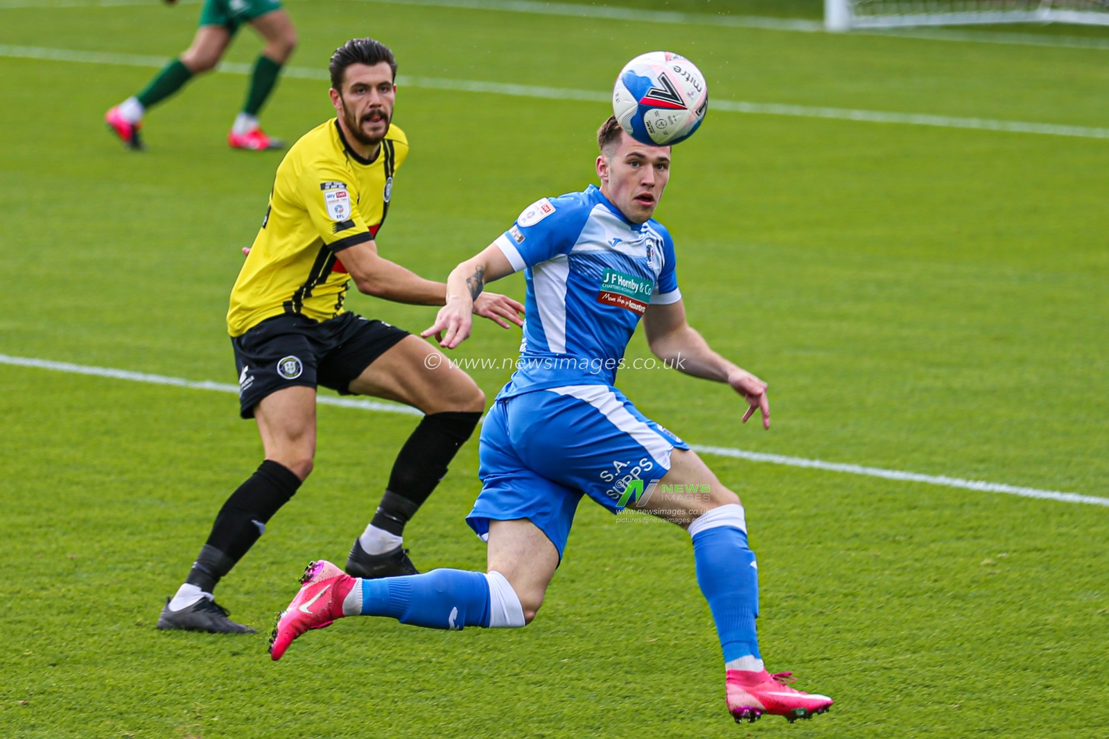 Connor Hall (20) of Harrogate Town and Josh Kay (11) of Barrow look to chase the ball