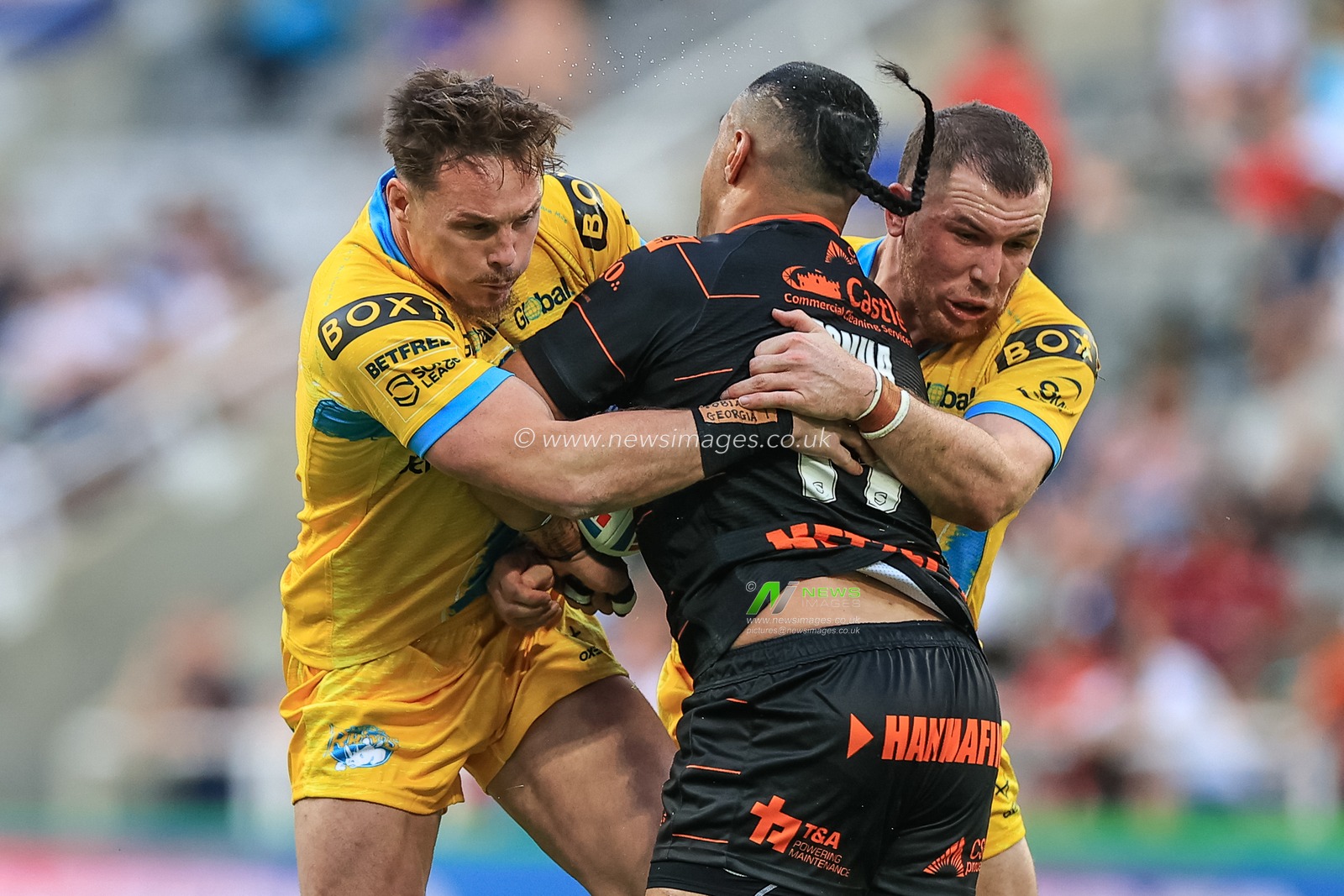 Mahe Fonua #17 of Castleford Tigers is tackled by James Donaldson #25 of Leeds Rhinos and Cameron Smith #17 of Leeds Rhinos