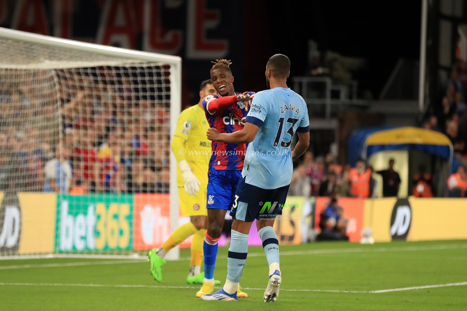 Wilfried Zaha #11 of Crystal Palace shoves Matthias Jorgensen #13 of Brentford after their dispute.
