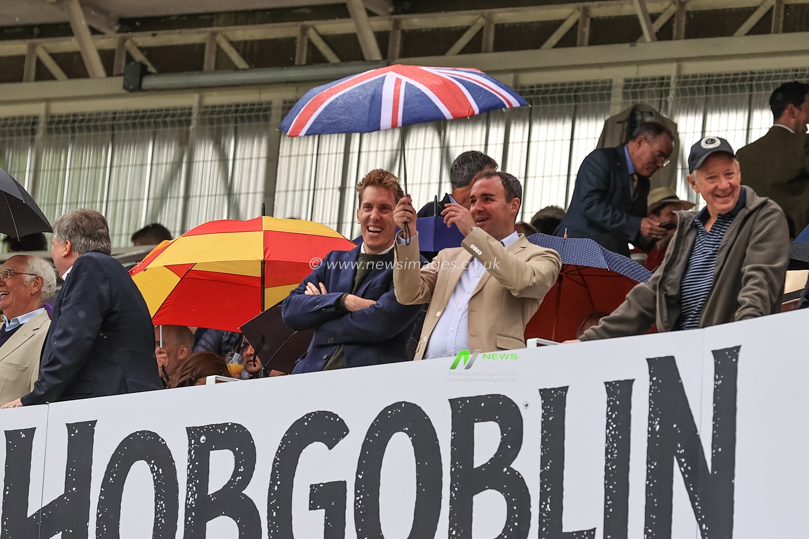 England supporters get under their brollies as rain halts the start of play on day 3