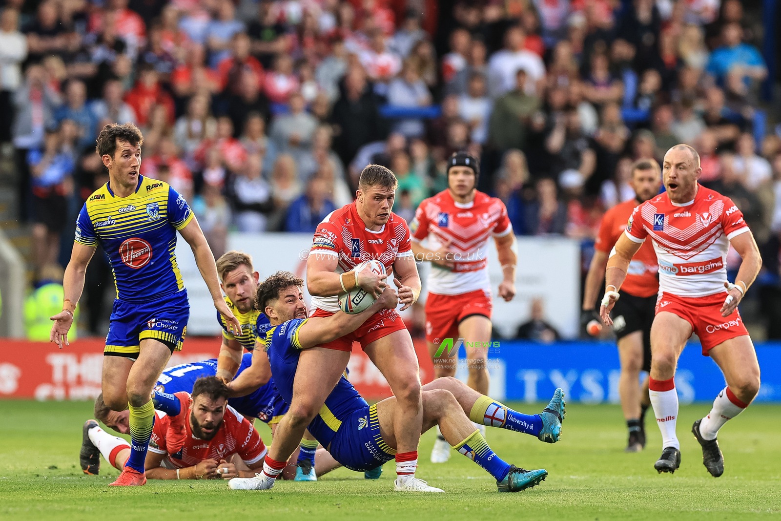 Morgan Knowles #13 of St Helens is tackled by Toby King #4 of Warrington Wolves