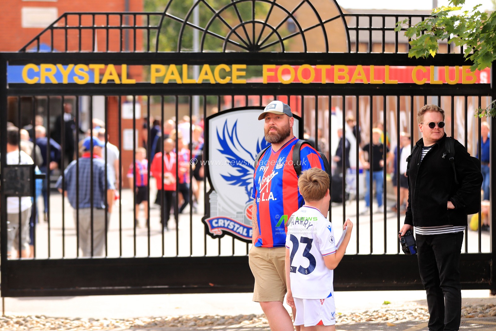 A Crystal Palace fan and his son stand in front of the club gates prior to kick off.