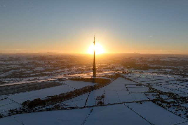 The sun sets over Emley Moor transmitting tower and the snow covered village of Emley as Sub-zero temperatures continue to hamper the north of the United Kingdom; Emley, Huddersfield, United Kingdom, 10th January 2025

(Photo by Mark Cosgrove/News Images)