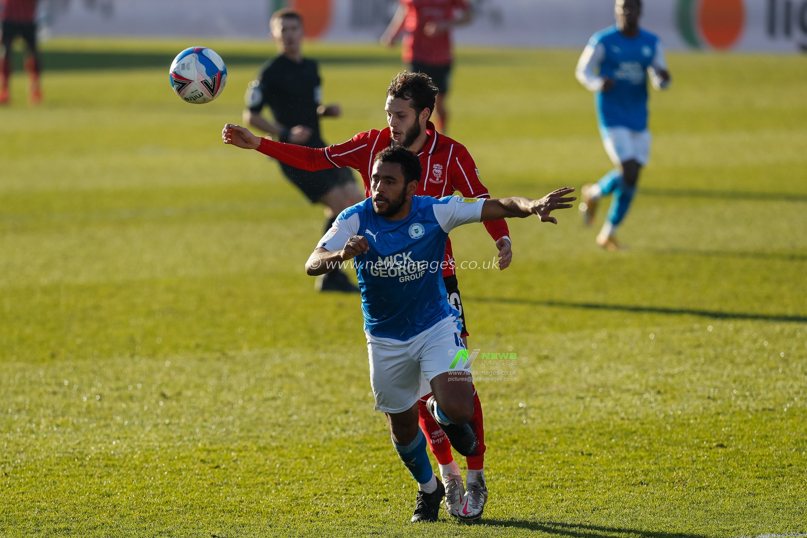 Nathan Thompson #4 of Peterborough United and Jorge Grant #10 of Lincoln City chase the ball