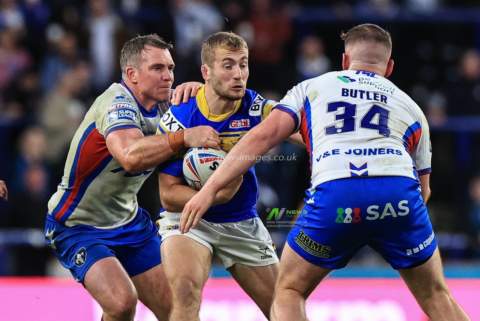 Jarrod O'Connor of Leeds Rhinos is tackled by Matty Ashurst #11 of Wakefield Trinity and Rob Butler #34 of Wakefield Trinity