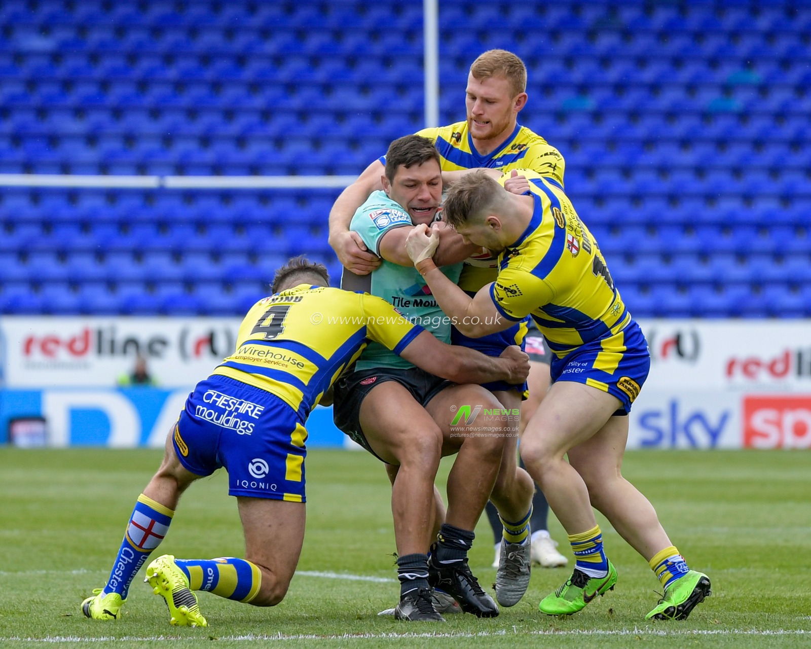 Ryan Hall (5) of Hull KR is tackled by Matt Davis (15), Toby King (4) and Jack Hughes (12) of Warrington Wolves