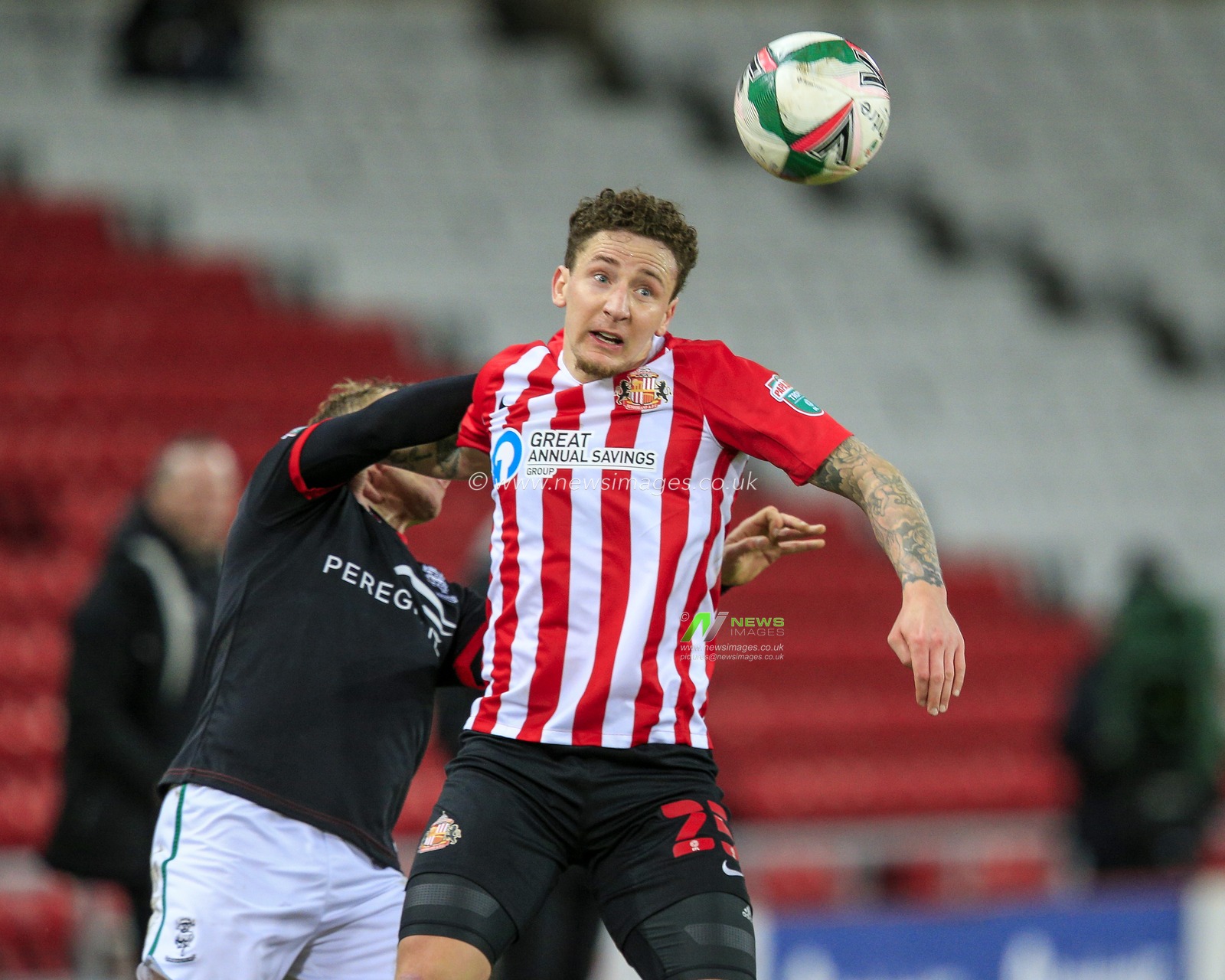 Callum McFadzean #25 of Sunderland fends off a challenge from Anthony Scully #11 of Lincoln City