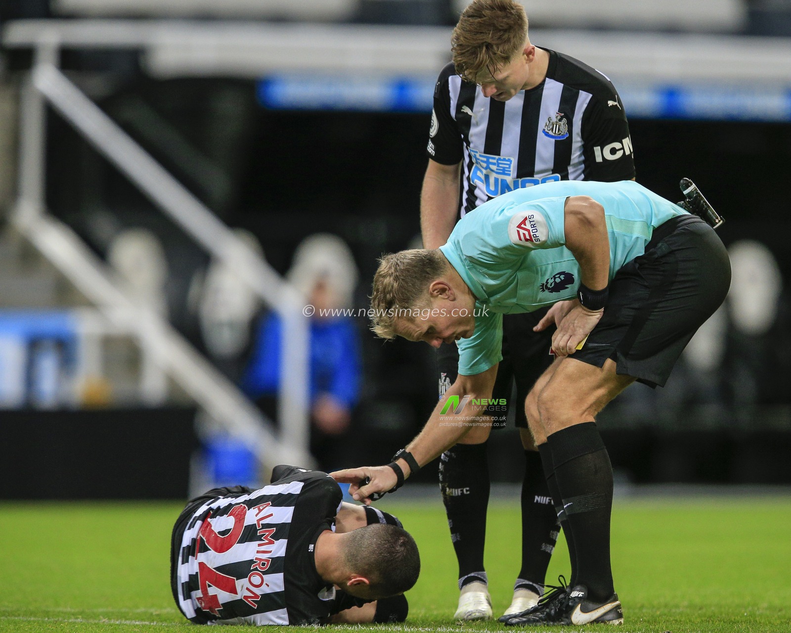 Referee Graham Scott checks on Miguel AlmirÃ³n #24 of Newcastle United after he is fouled