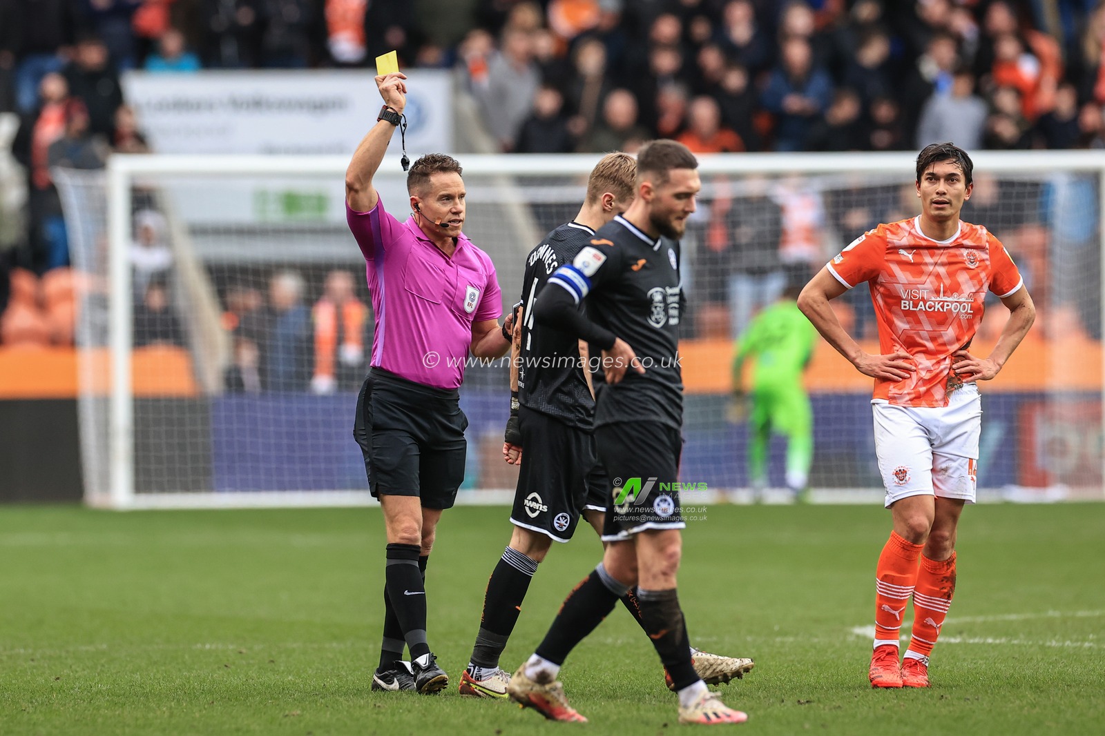 referee Steve Martin gives Flynn Downes #4 of Swansea City a yellow card