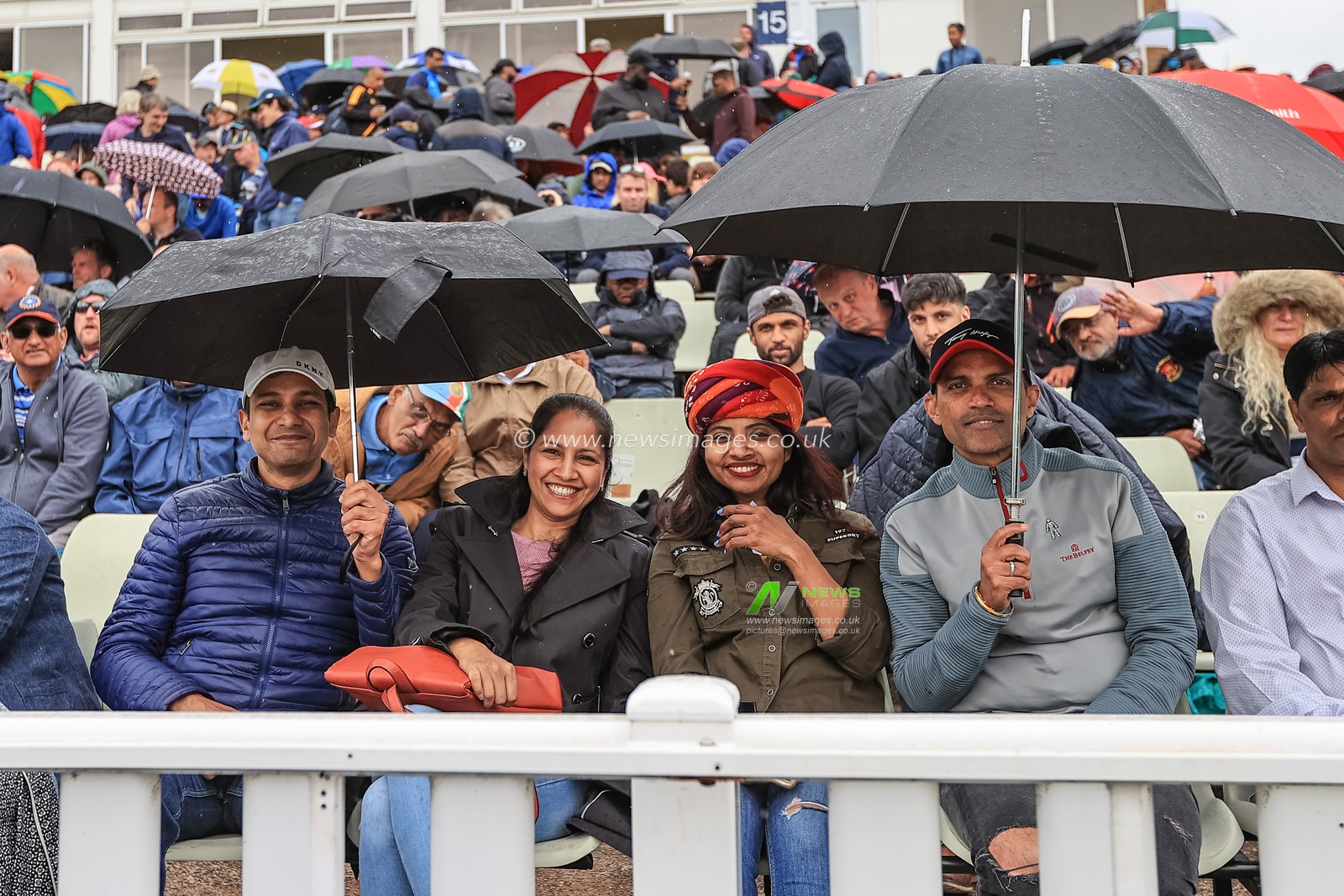 Fans get under their brollies as rain stops play for a second time