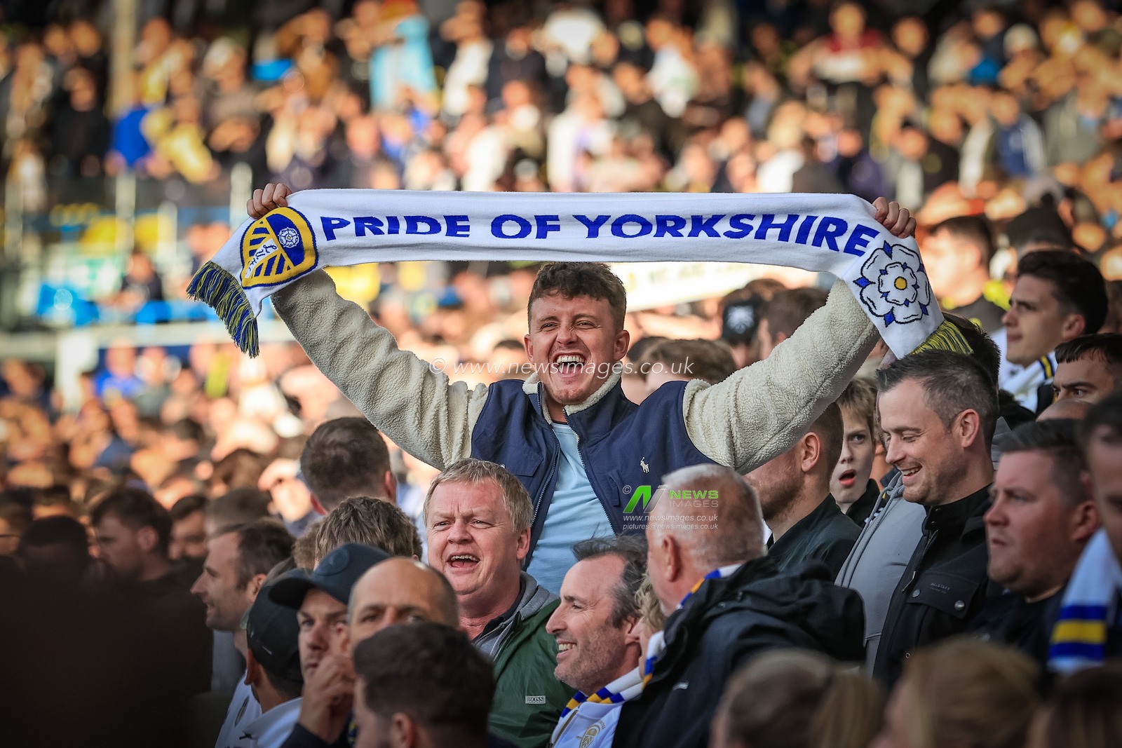 A Leeds United fan holds his scarf up high as all the crowd sing â€œMarching on togetherâ€