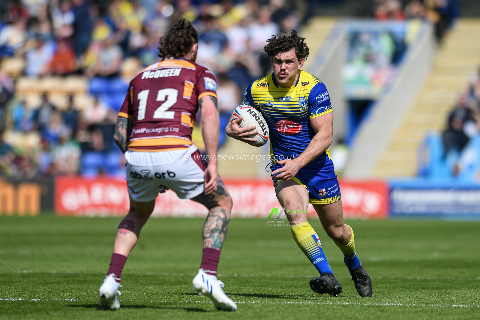 Rob Mulhern #19 of Warrington Wolves looks for a way past Chris McQueen #12 of Huddersfield Giants