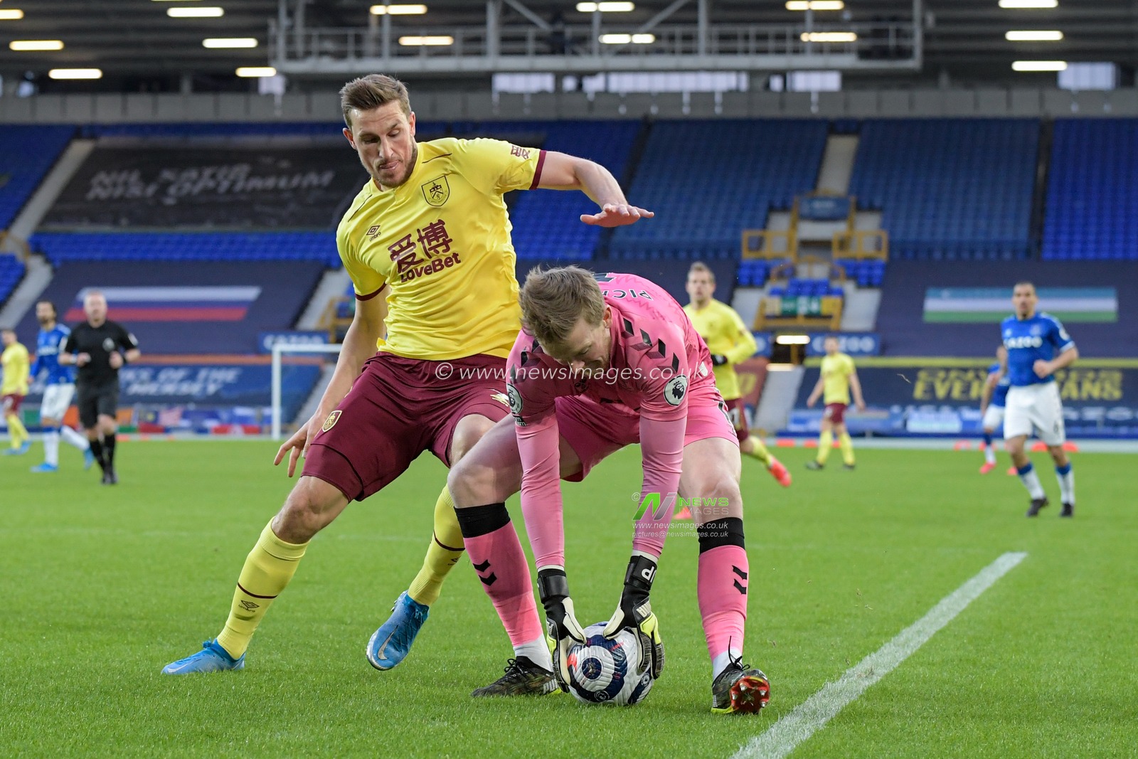 Jordan Pickford #1 of Everton picks up the ball while under pressure from Chris Wood #9 of Burnley