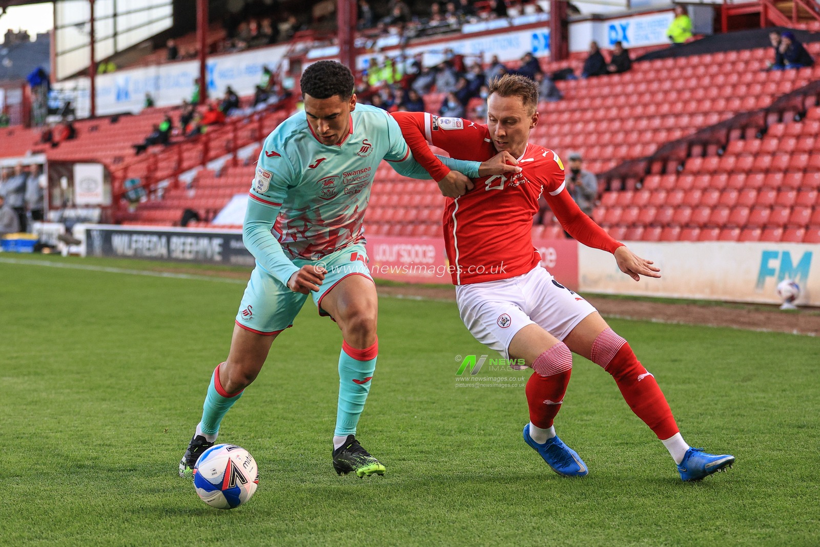 Ben Cabango #44 of Swansea City holds off Cauley Woodrow #9 of Barnsley