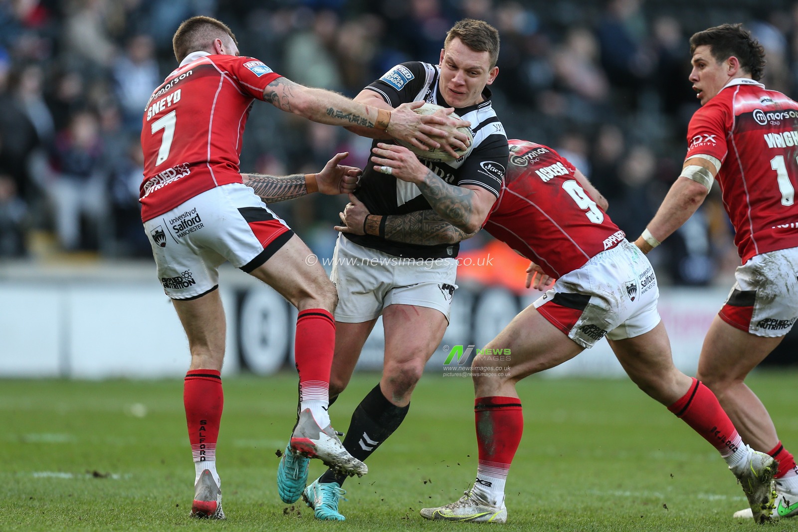 Jordan Lane #13 of Hull FC goes through the tackle of Marc Sneyd #7 and Andy Ackers #9 of Salford Red Devils