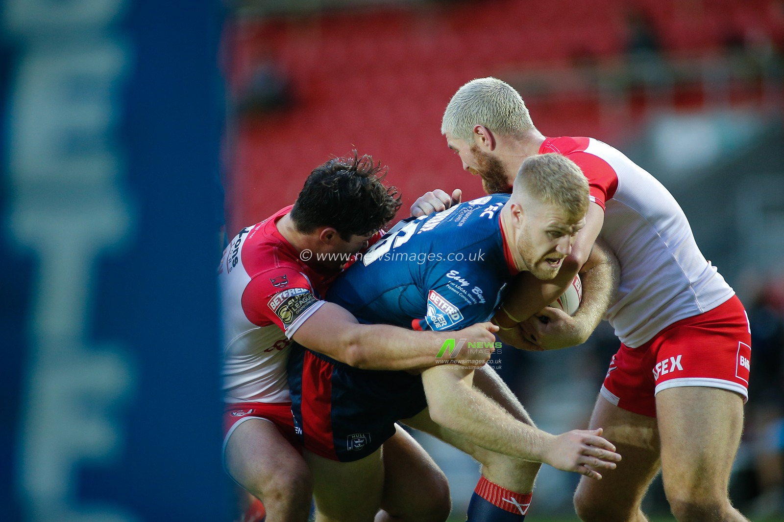 Dan Murray (16) of Hull KR tackled by Lachlan Coote (1) and Kyle Amor (16) of St Helens.