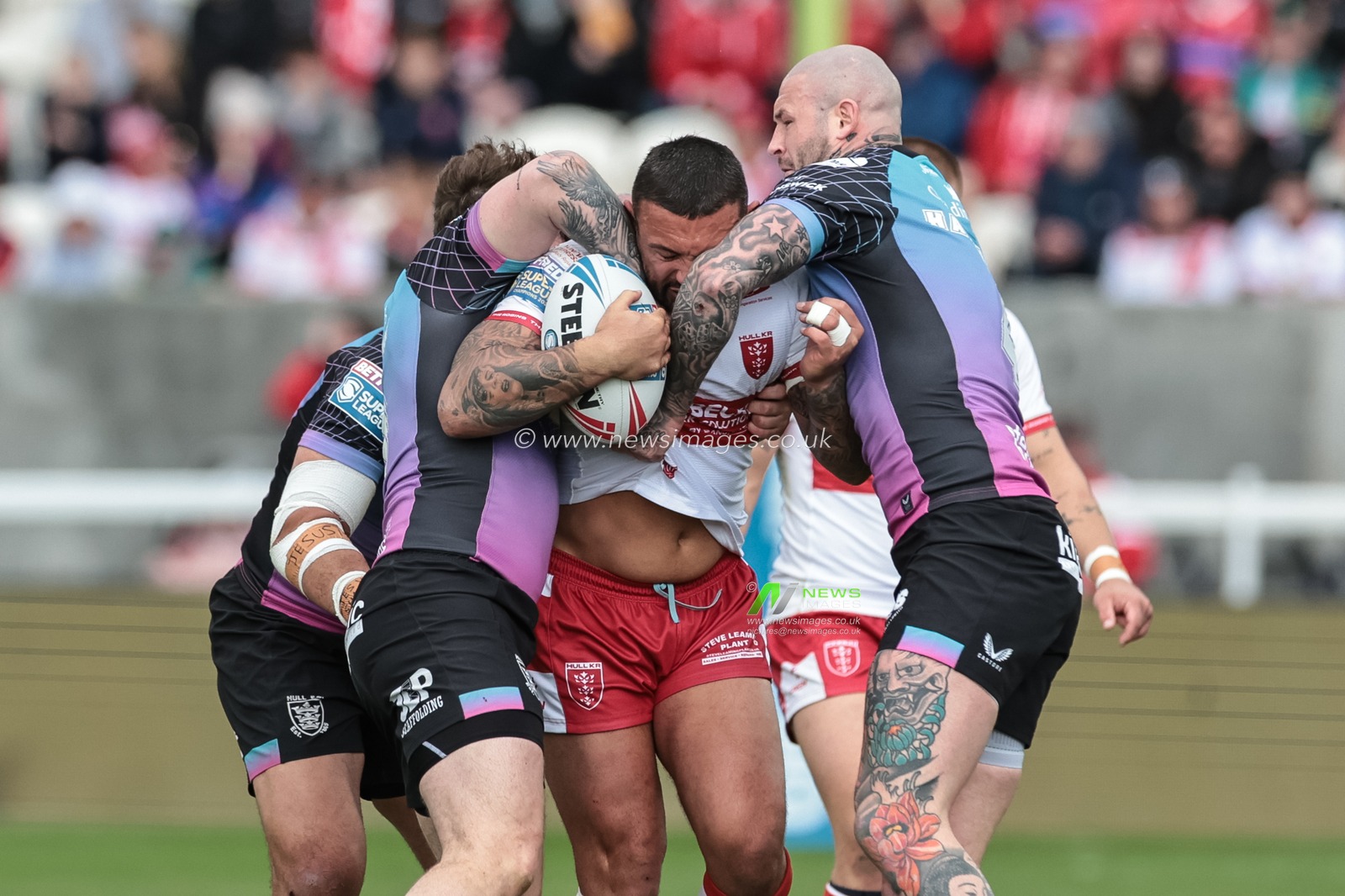 Elliot Minchella of Hull KR is tackled by Amir Bourouh of Hull F.C. and Zak Hardaker of Hull F.C. during the Betfred Super League round 7 match Hull KR vs Hull FC at Sewell Group Craven Park, Hull, United Kingdom on 03 April 2026

(Photo by Mark Cosgrove/News Images)