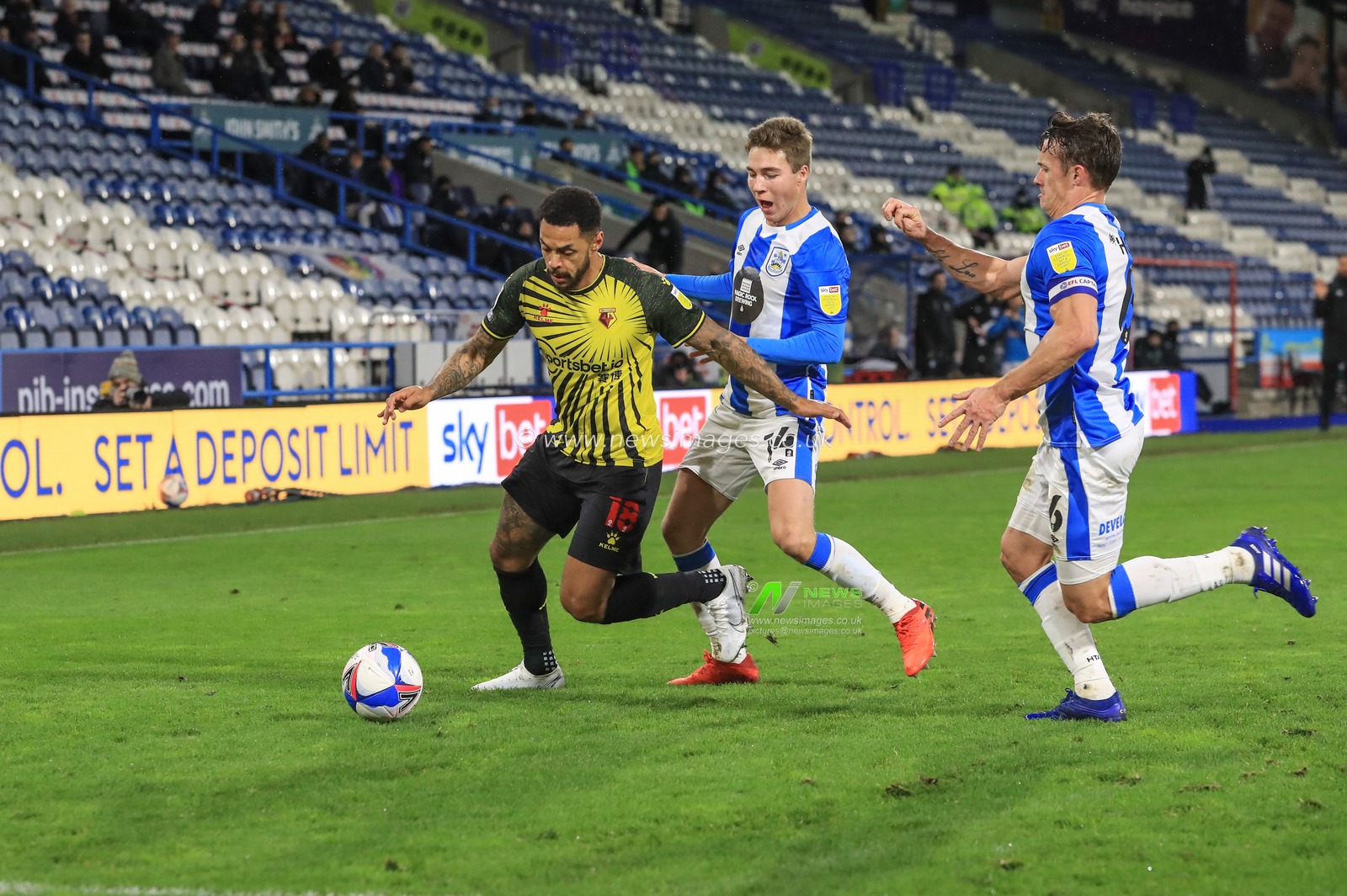 Andre Gray #18 of Watford holds the ball while under pressure from Carel Eiting #14 of Huddersfield Town