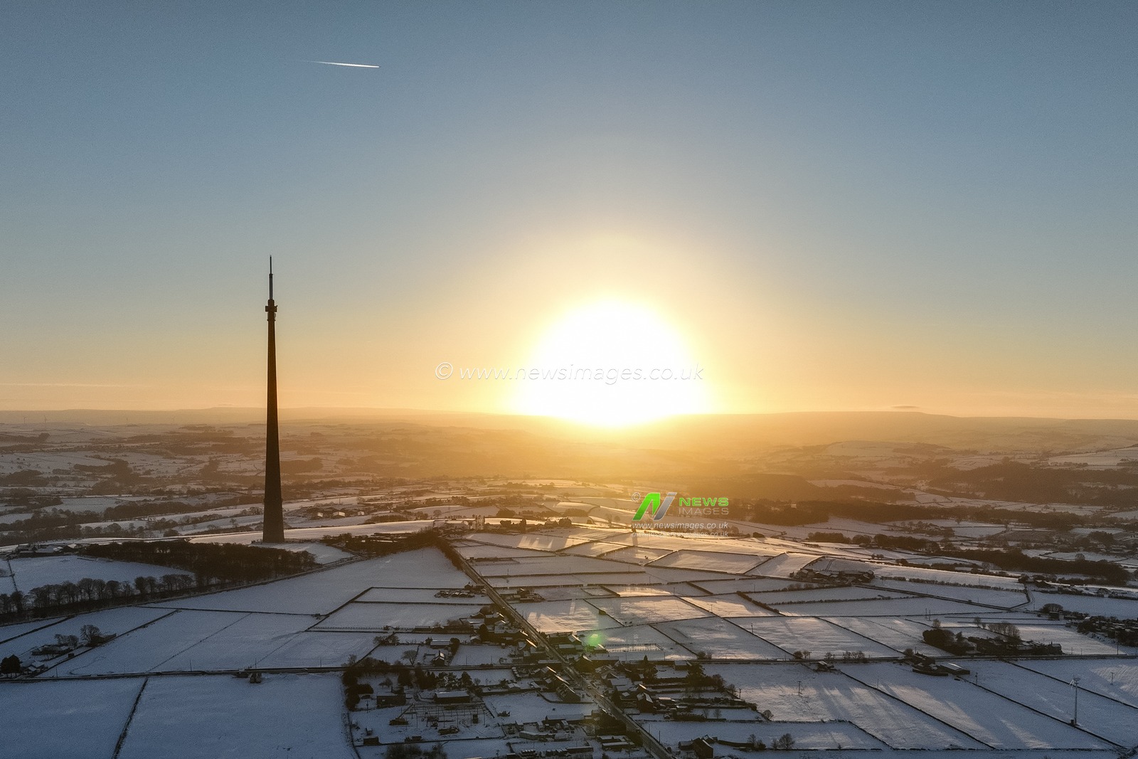 The sun sets over Emley Moor transmitting tower and the snow covered village of Emley as Sub-zero temperatures continue to hamper the north of the United Kingdom; Emley, Huddersfield, United Kingdom, 10th January 2025

(Photo by Mark Cosgrove/News Images)