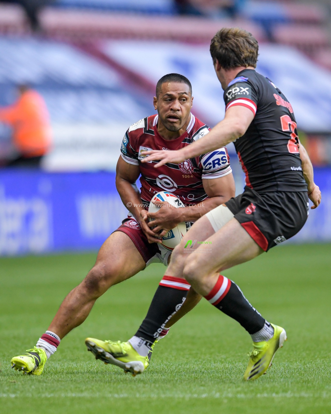 Willie Isa (11) of Wigan Warriors looks for a way past Dan Sarginson (23) of Salford Red Devils