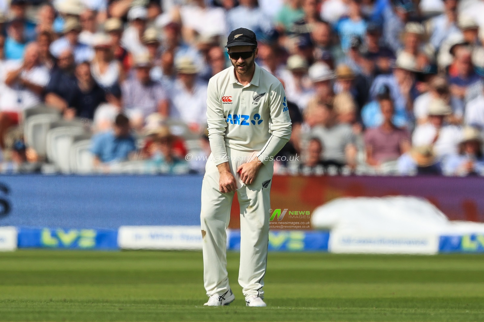 Kane Williamson of New Zealand polishes the ball