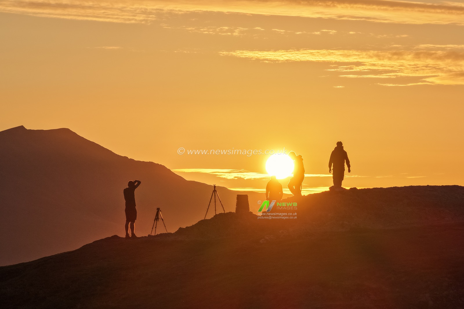 Photographers take pictures as the sun rises from the summit of Catbells overlooking Derwent Water and the town of Keswick In the Lake District, Cumbria, United Kingdom, 19th June 2025.

(Photo by Mark Cosgrove/News Images)