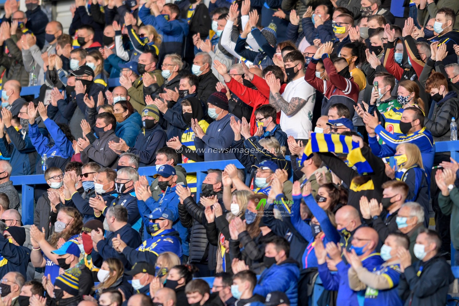 The Warrington Wolves fans welcome the team to the pitch at the start of the game