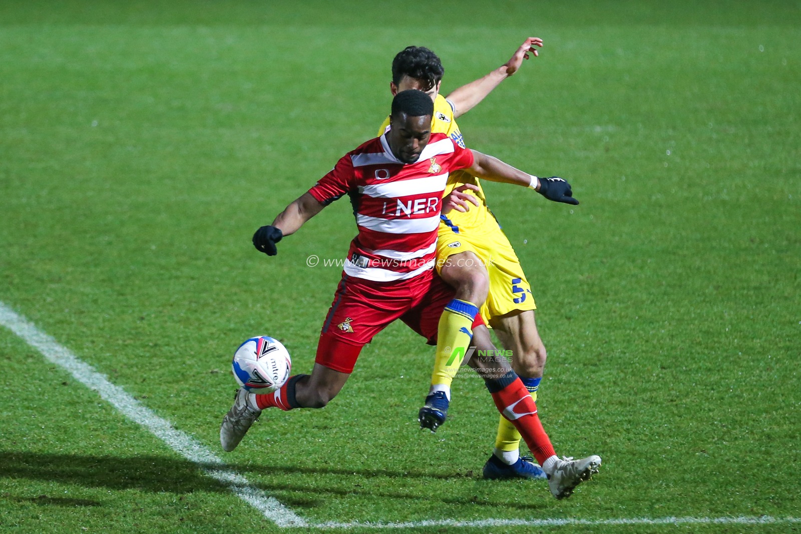 Will Nightingale #5 of AFC Wimbledon and Fejiri Okenabirhie #9 of Doncaster Rovers battle for the ball