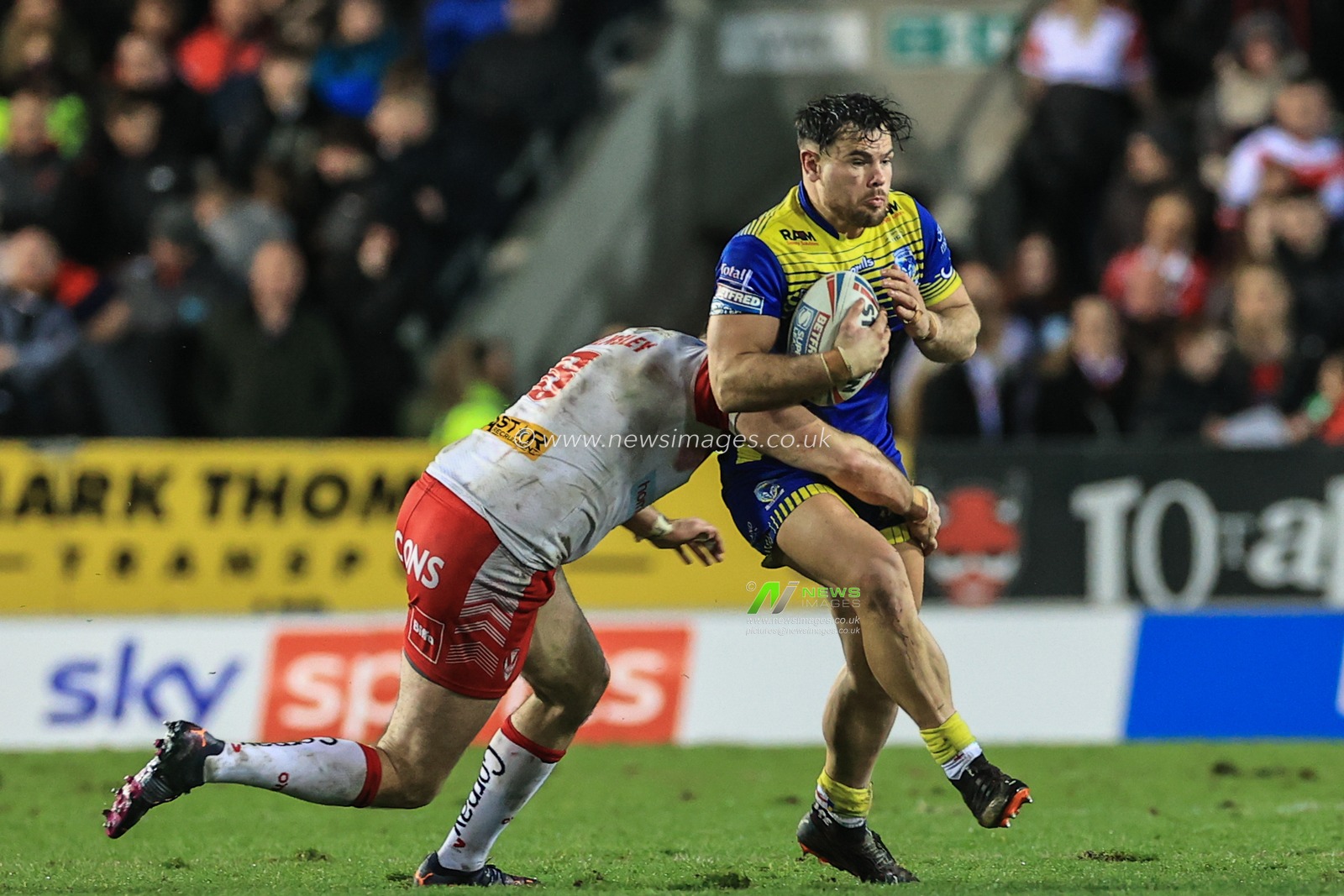 Joe Philbin #8 of Warrington Wolves is tackled by Alex Walmsley #8 of St Helens