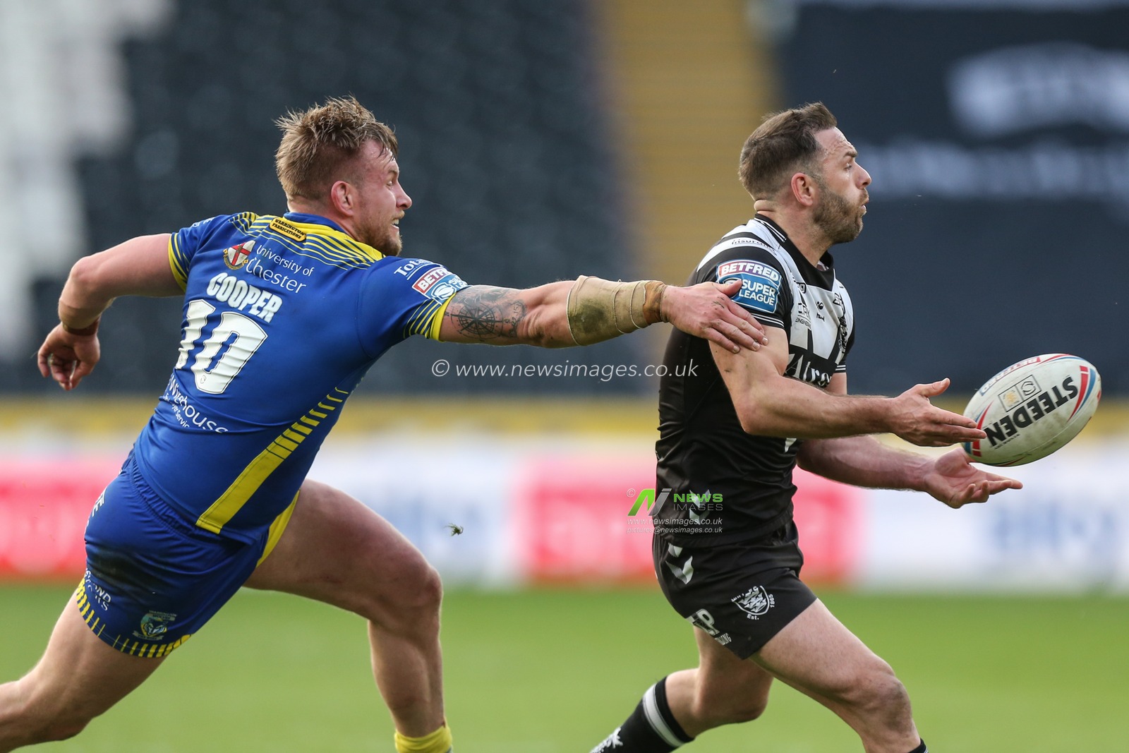 Luke Gale #7 of Hull FC gets the ball away before being tackled by Mike Cooper #10 of Warrington Wolves