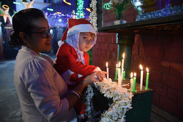 A little boy with his Mother Candle Light pray inside St. Teresa's Church on the occasion Christmas Eve marking the birth of Jesus Christ on December 24,2024 in Kolkata,India.(Photo: Debajyoti Chakraborty/News Images)