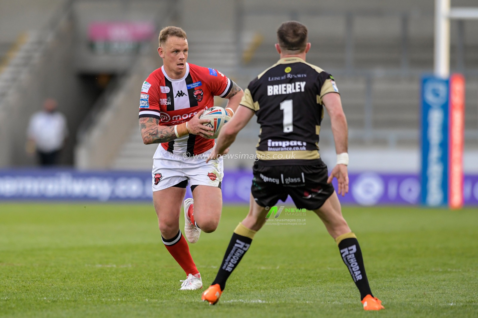 Kevin Brown (7) of Salford Red Devils looks for a way past Ryan Brierley (1) of Leigh Centurions