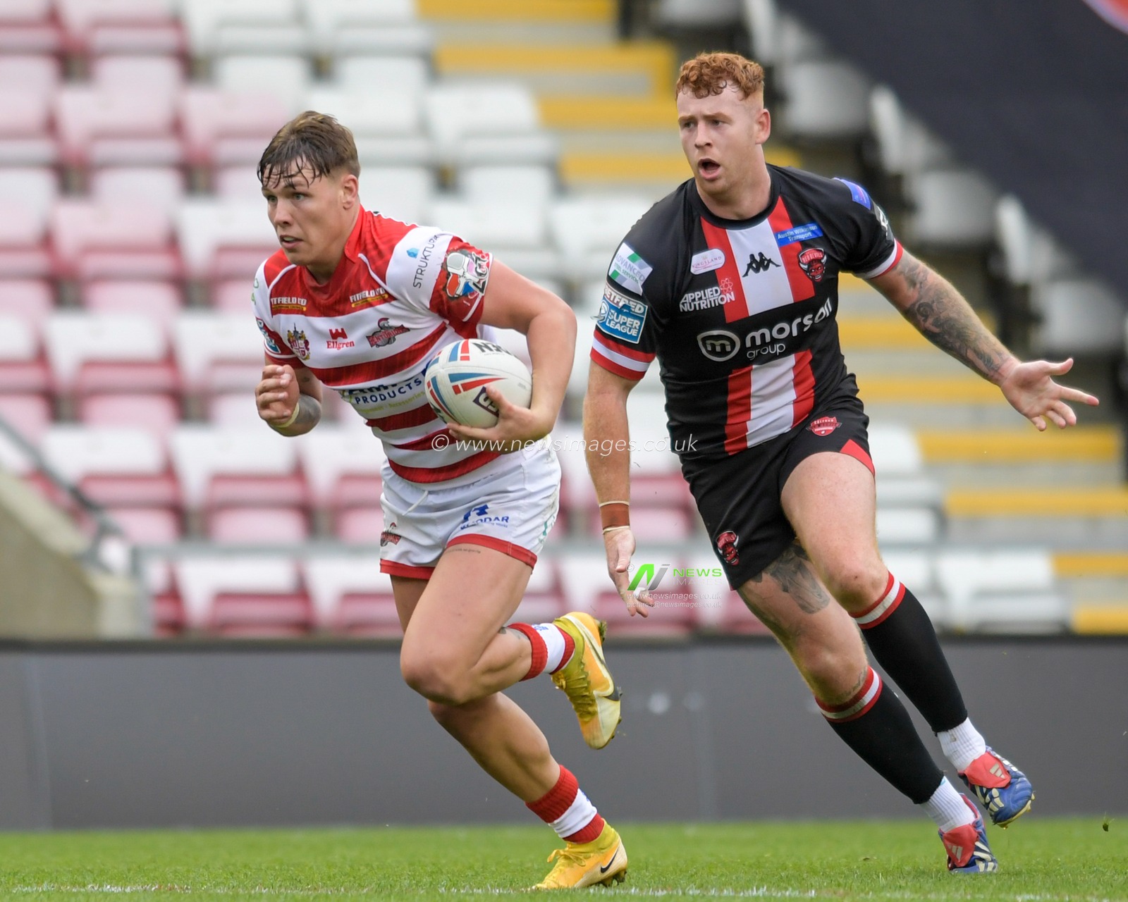 Keanan Brand (24) of Leigh Centurions runs past Harvey Livett (20) of Salford Red Devils