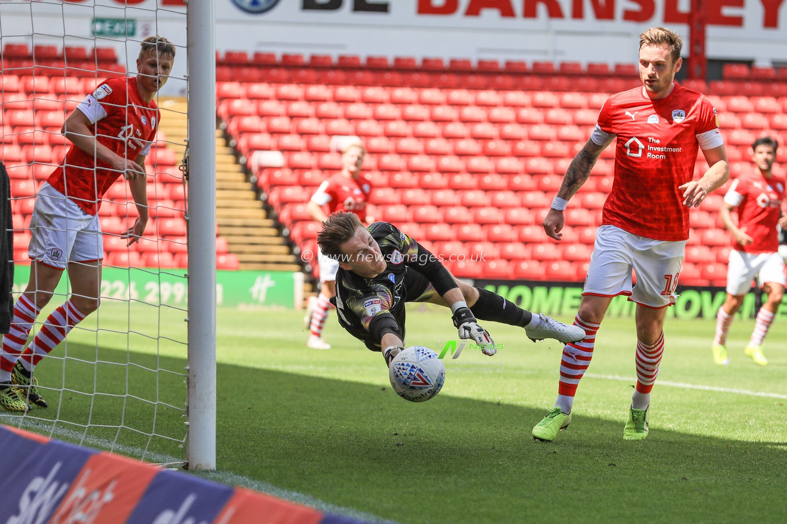 Jack Walton (13) of Barnsley makes a fingertip save from Mason Bennett (20) of Millwall