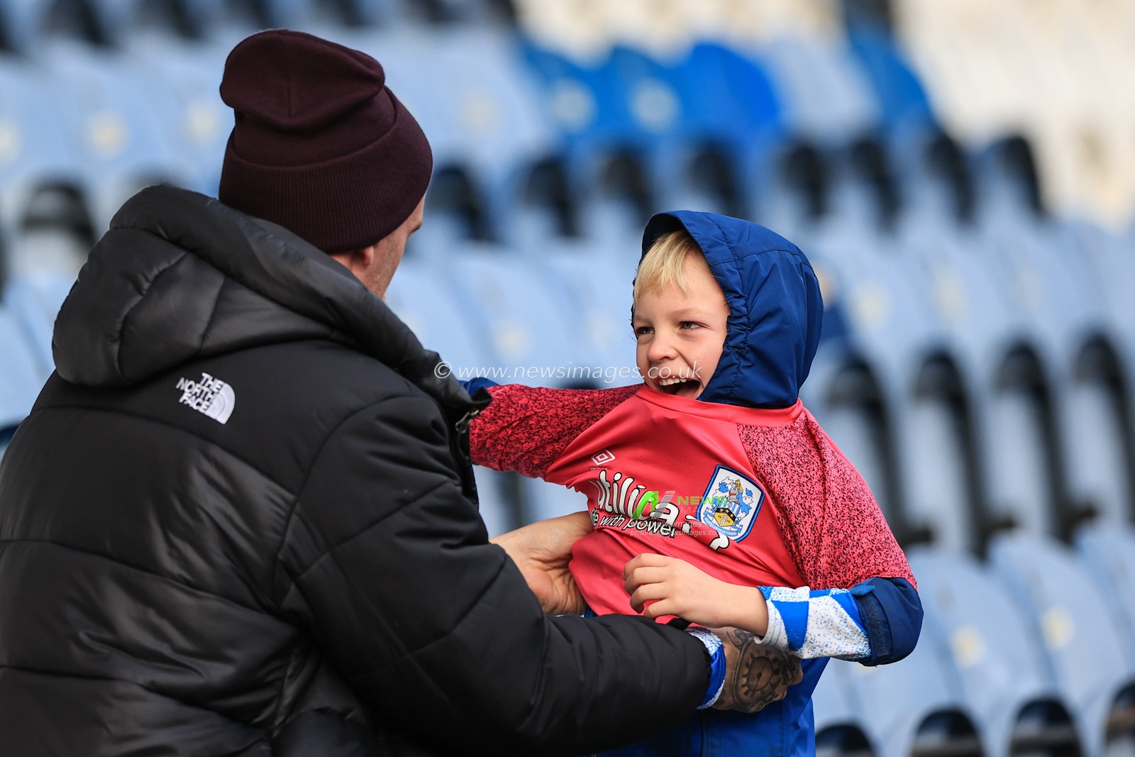 A young fan is helped into her Huddersfield top