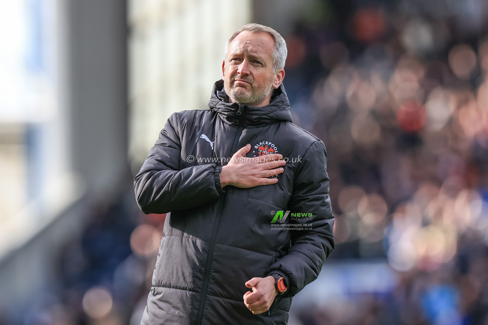 Neil Critchley head coach of Blackpool pats his Blackpool badge in front of the traveling fans