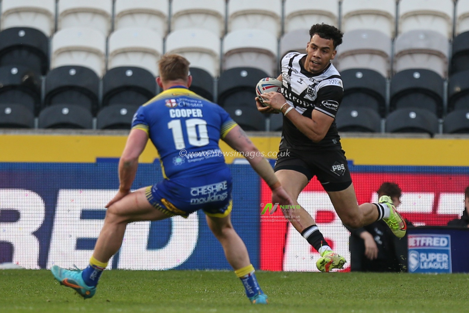 Darnell McIntosh #5 of Hull FC runs at Mike Cooper #10 of Warrington Wolves