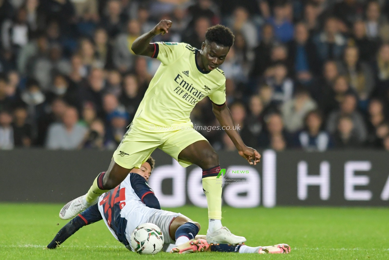 Bukayo Saka #7 of Arsenal jumps over the tackle attempt from Zac Ashworth #35 of West Bromwich Albion