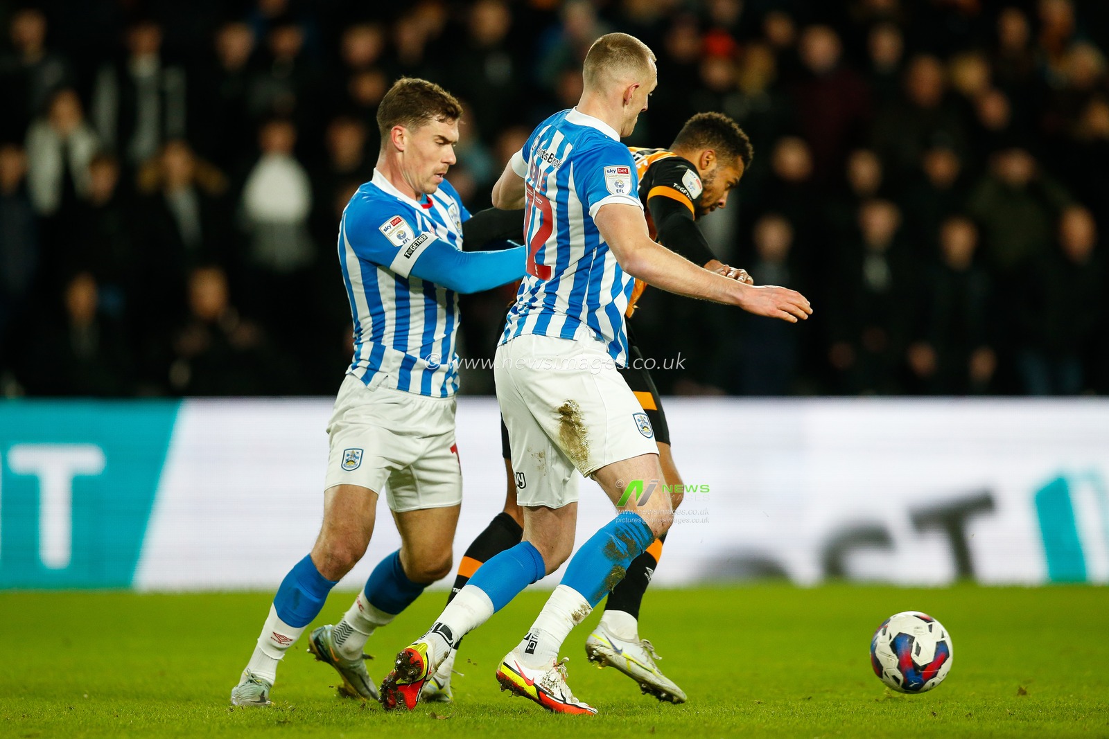 Cyrus Christie #33 of Hull City holds off  Will Boyle #12 of Huddersfield Town and Josh Ruffels #14 of Huddersfield Town during the Sky Bet Championship match Hull City vs Huddersfield Town at MKM Stadium, Hull, United Kingdom, 14th January 2023

(Photo by Ben Early/News Images)