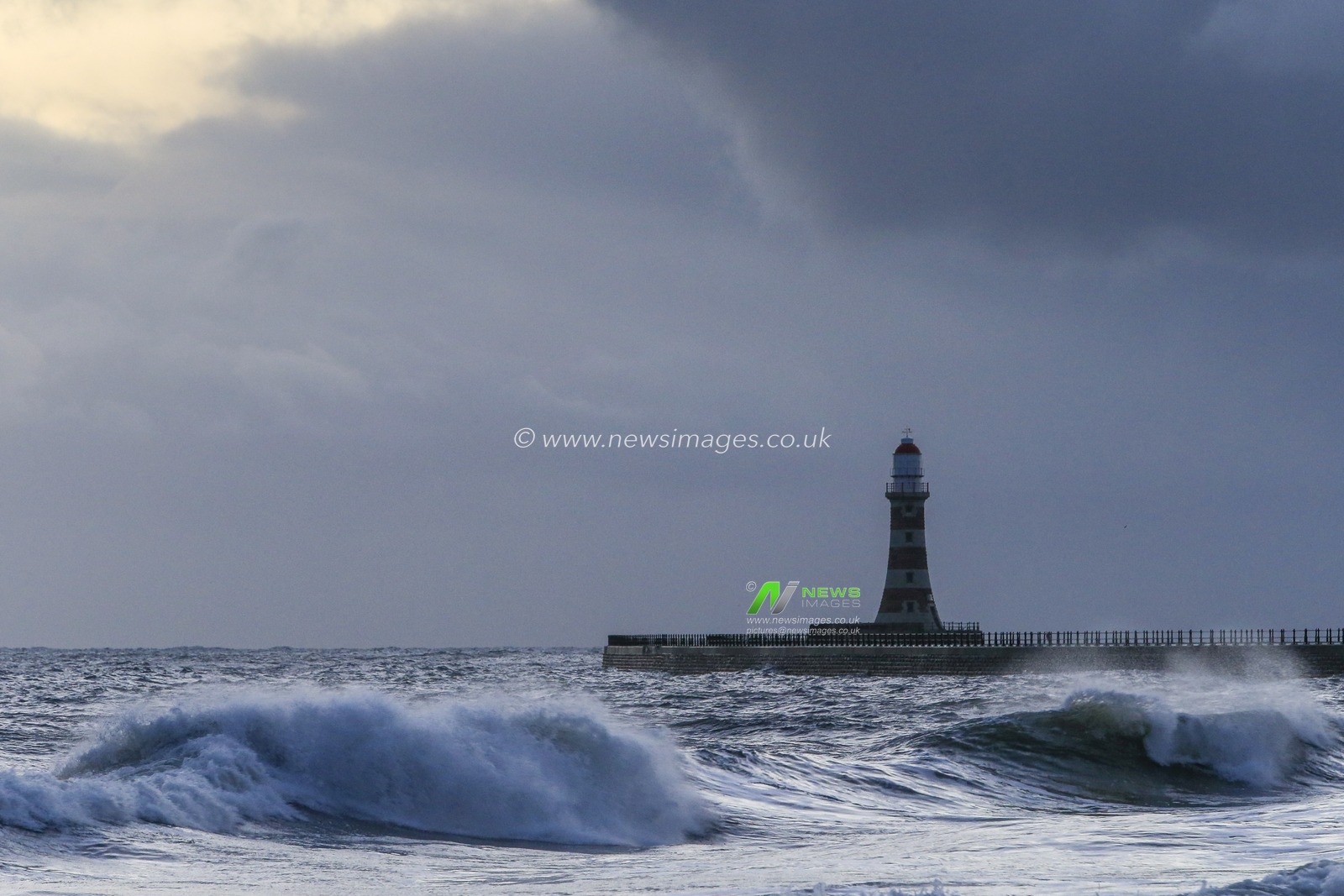 Waves crash in front Roker Pier and Lighthouse just before daybreak in Sunderland