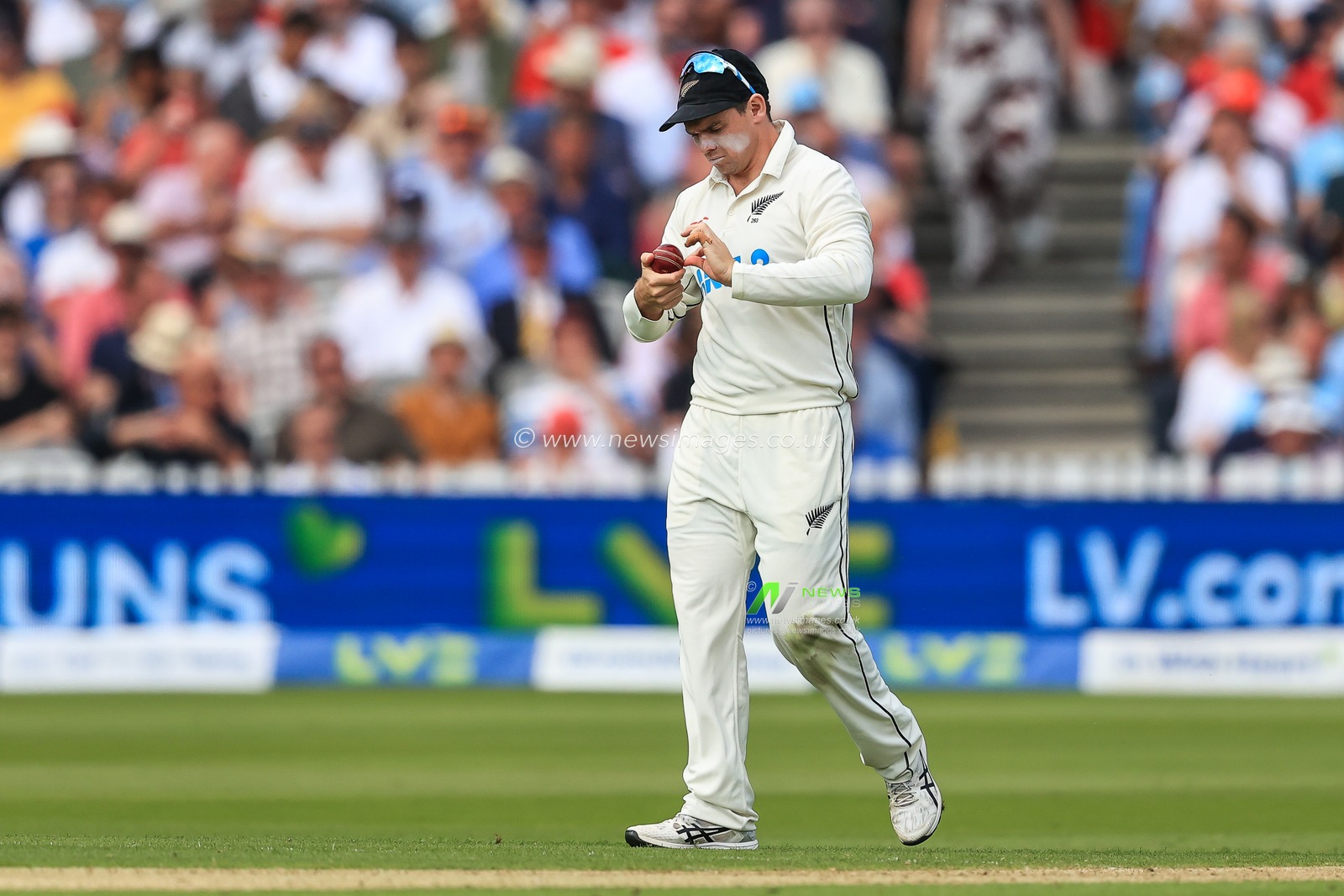 Tom Latham of New Zealand polishes the ball
