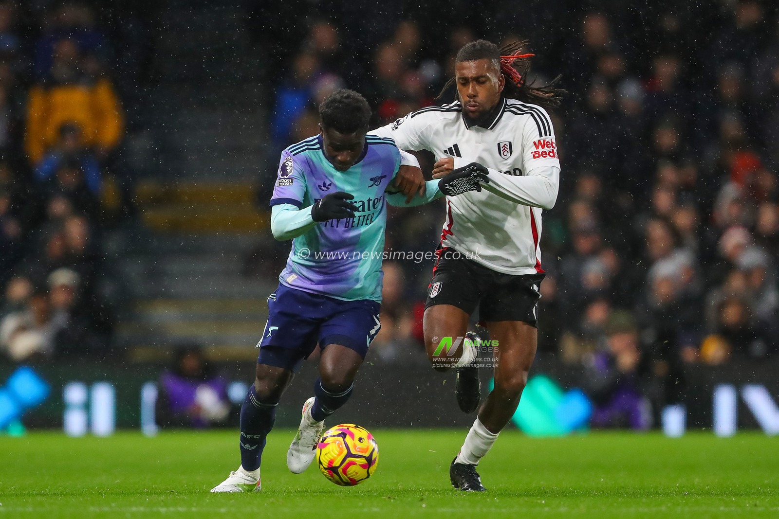 Bukayo Saka of Arsenal and Alex Iwobi of Fulham battle for the ball during the Premier League match Fulham vs Arsenal at Craven Cottage, London, United Kingdom, 8th December 2024

(Photo by Gareth Evans/News Images)