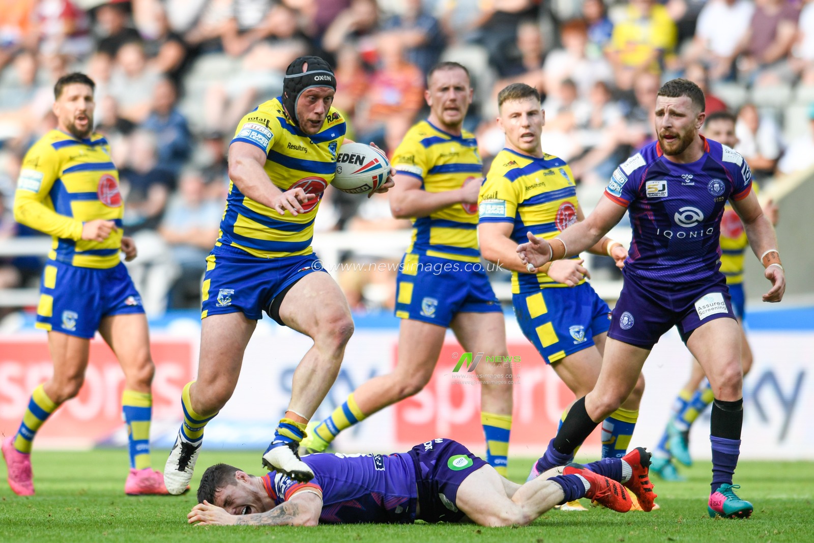 Chris Hill (8) of Warrington Wolves jumps over the tackle attempt from John Bateman (13) of Wigan Warriors